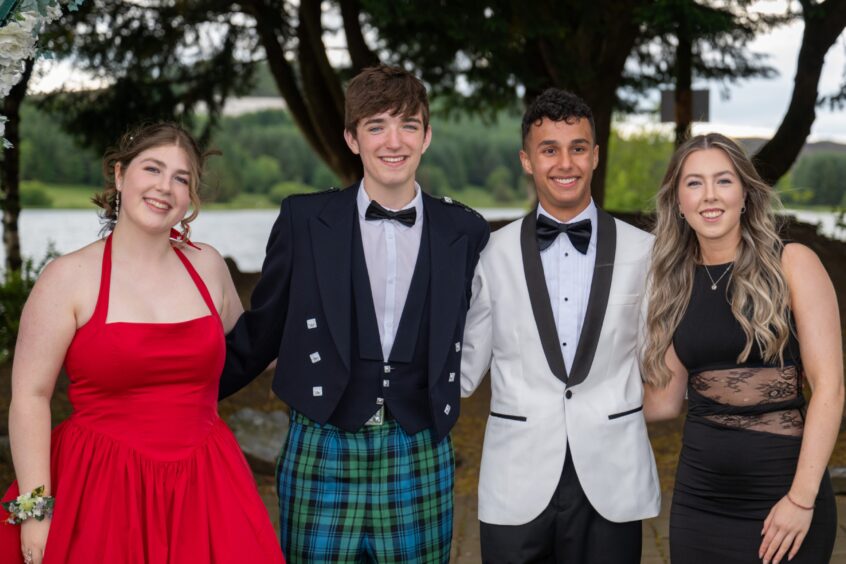 Two boys and two girls smile and pose outside. 