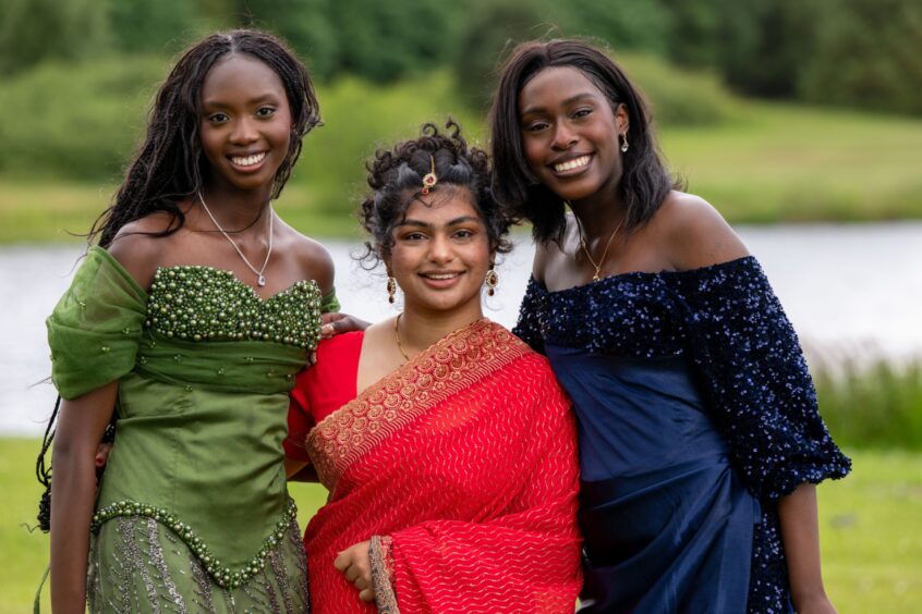 A female trio in colourful dresses with Piperdam Loch behind them. 