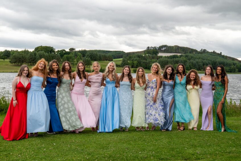 A group of girls standing on a lawn with Piperdam Loch behind them. 