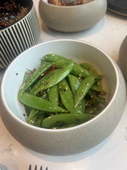 A bowl of cooked snow peas.