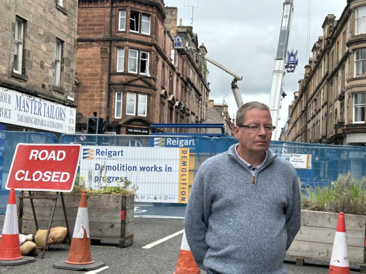 Steve Black with the demolition site behind him. 