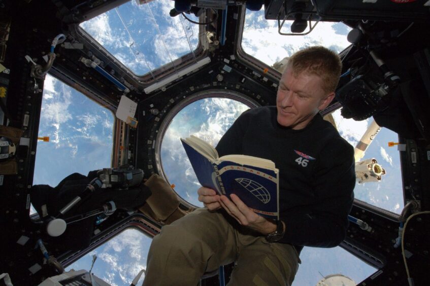 Tim Peake reading a book in space.