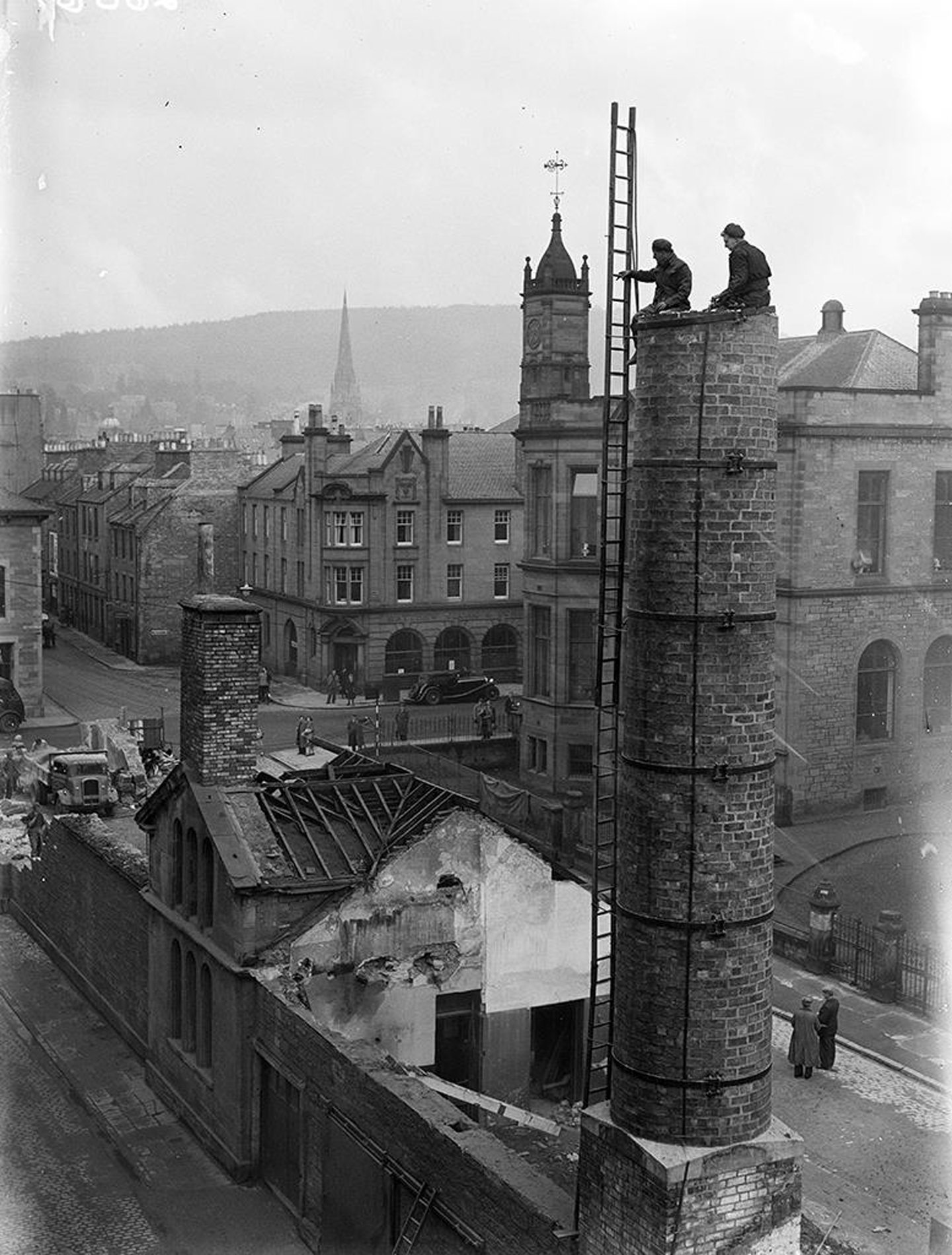 two men atop a chimney stack as the Mill Street washhouse is demolished