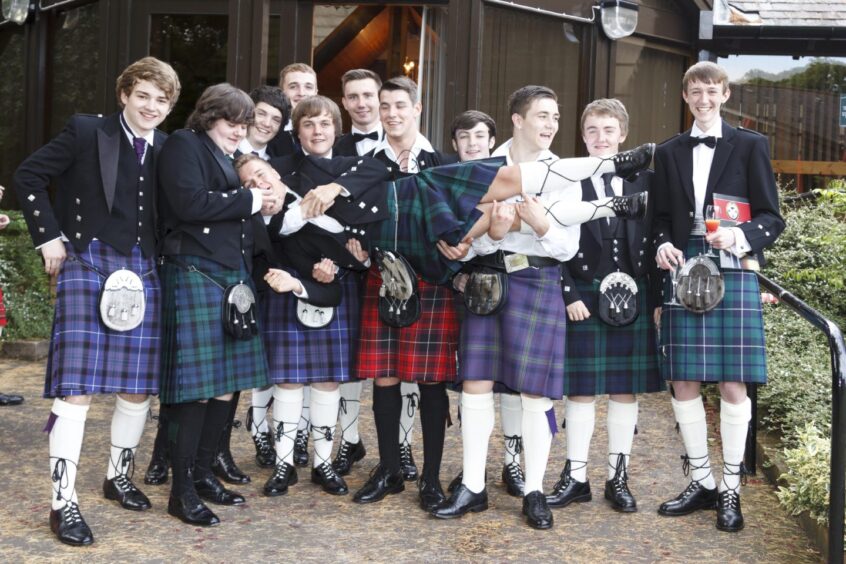 Pupils in kilts at the sixth year dinner dance in August 2015. They are holding up another kilted pupil