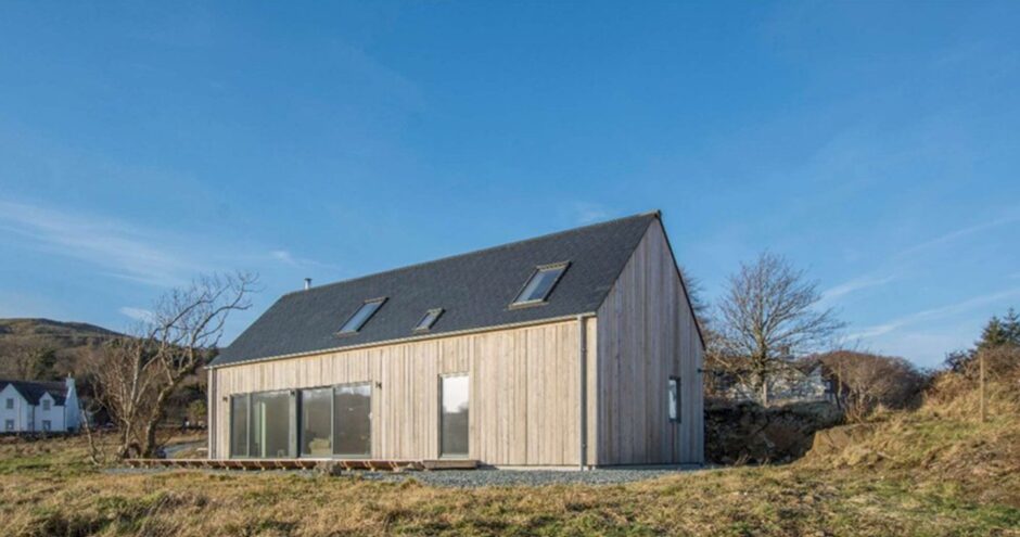 One-storey timber house with large glass windows in rural setting