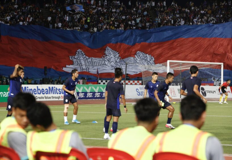 Cambodia players warm-up in front of a packed stadium.