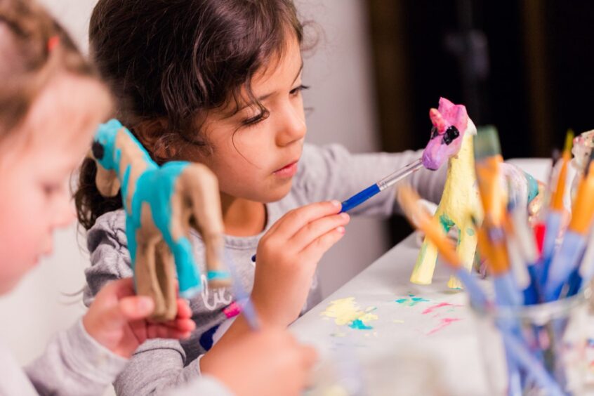 A girl painting a small model unicorn. 