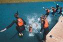People in lifejackets jumping into water.