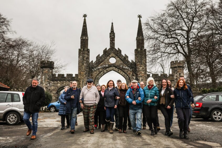 Group of Kenmore residents walking in front of gates to Taymouth Castle, Kenmore