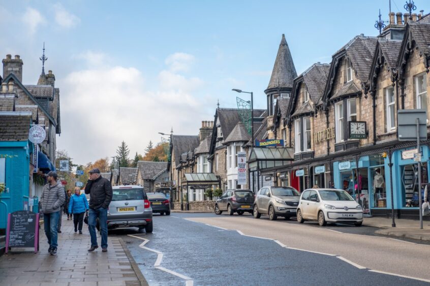 Pitlochry street scene with pedestrians walking past shops and hotels