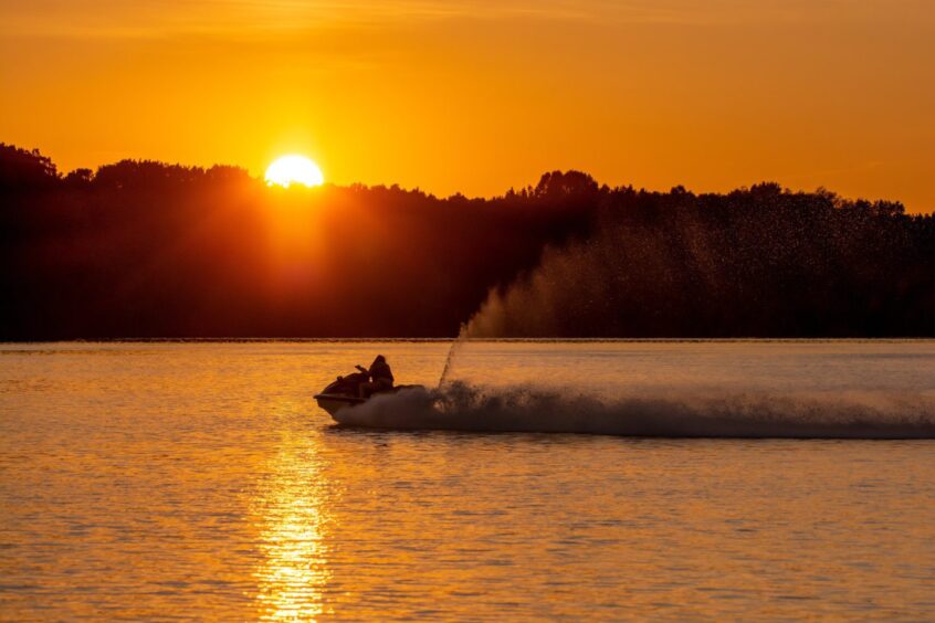 person on jet-ski as sun goes down over river
