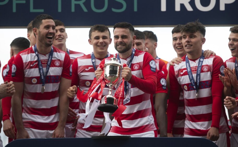 Reghan Tumilty lifts the SPFL Trust trophy in front of his Hamilton team-mates.