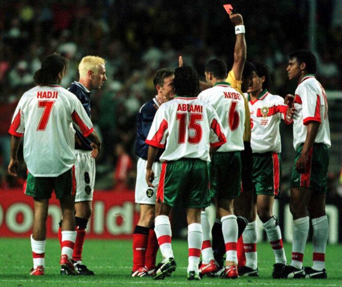 Mustapha Hadji Sr, No.7, looks on as Craig Burley is dismissed and Morocco hammer Scotland 3-0.