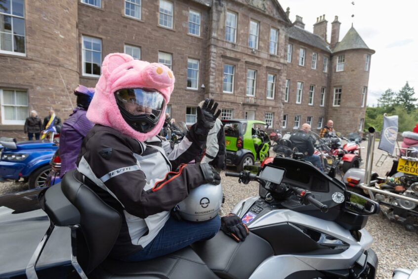Motorcyclist wearing a pink pig helmet cover poses on a silver bike during the 2025 Brechin Bike and Trike Fest gathering at Brechin Castle.