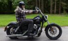 Bearded motorcyclist rides a black Harley-Davidson during the 2025 Bike and Trike Fest rideout from Brechin Castle in Angus.