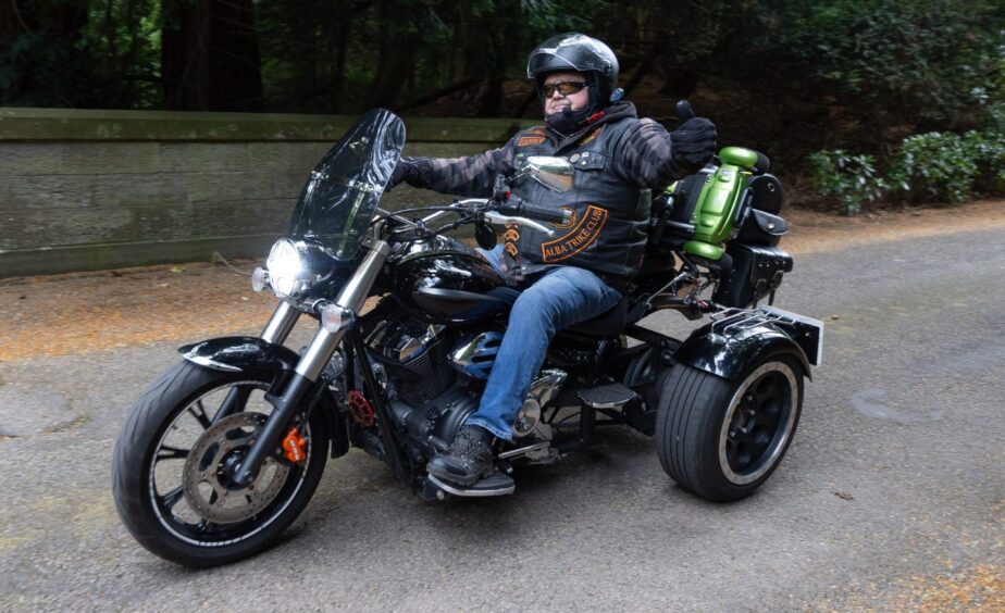Alba Trike Club member gives a thumbs-up while riding a black trike during the 2025 Brechin Bike and Trike Fest in Angus.