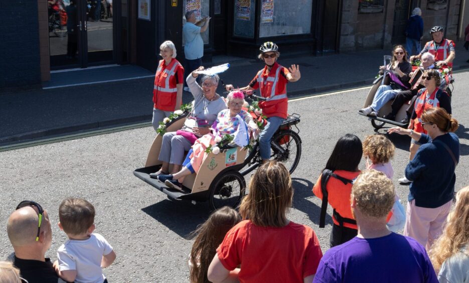 Carnoustie gala parade participants ride decorated trishaws through the town centre, waving to crowds gathered along the High Street on Saturday.