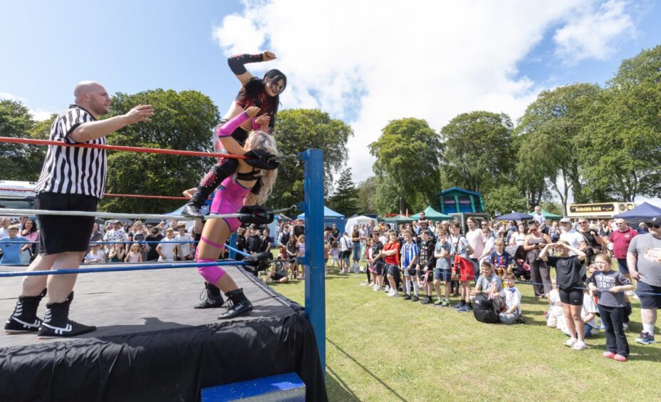 Two female SWE wrestlers battle in the ring as spectators watch during the first ever wrestling display at Carnoustie Gala Day 2025.