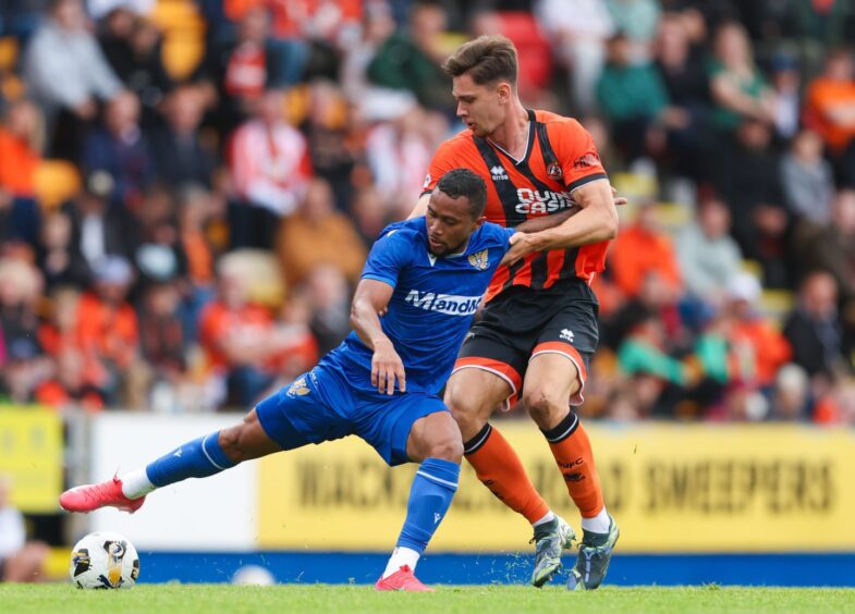 Victor Griffith holds off a Dundee United player.