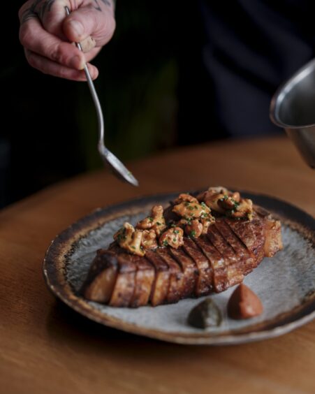 A large steak being plated as part of Haar's à la carte offering.