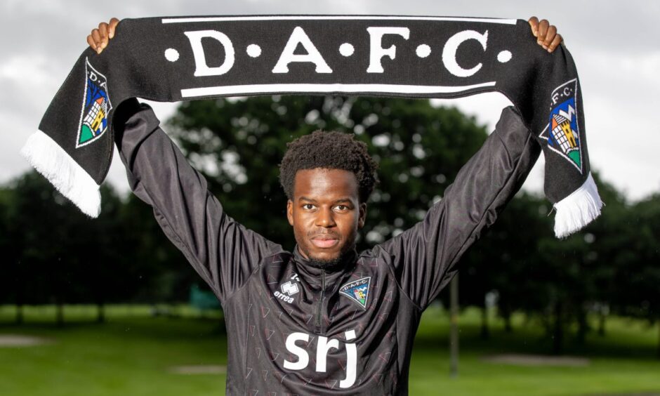 Alfons Amade holds a DAFC scarf above his head.