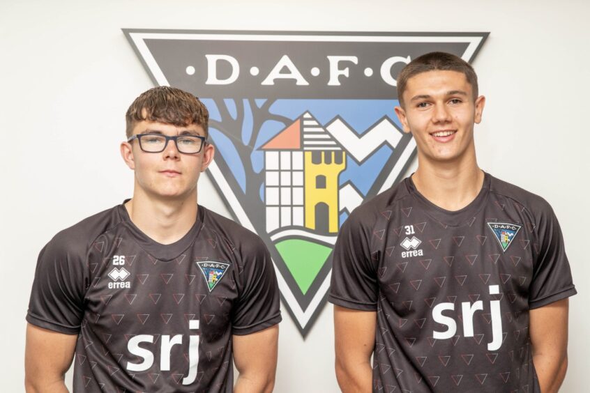 John Tod with brother Andrew in front of a large DAFC badge on the wall at East End Park.