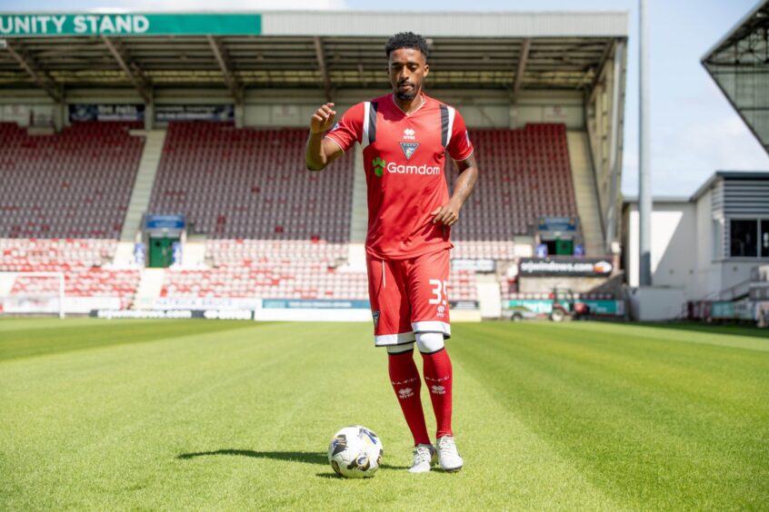 Tashan Oakley-Boothe kicks a ball as he models Dunfermline's new away kit.