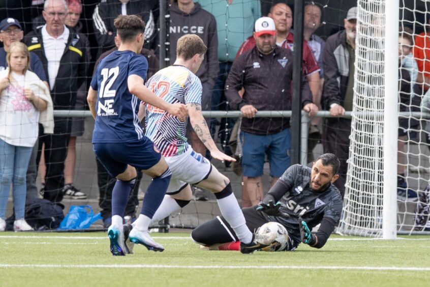 Pars goalkeeper Deniz Mehmet dives on the ground to gather a ball.