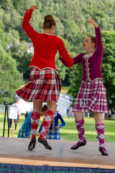 Two girls arms linked on stage in highland dance gear