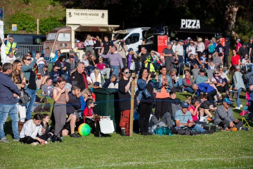 Spactators watching Kenmore Highland Games with food trucks behind