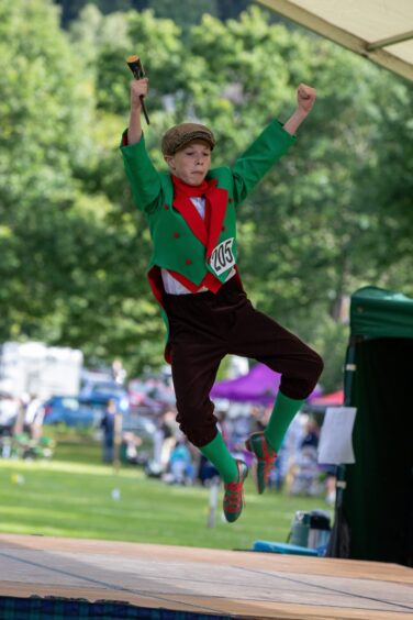 Young boy in green and black outfit dancing on stage