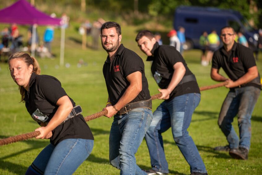 Tug of war team in black t shirts, with one woman at front and men behind