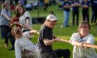 People doing tug of war, one in a cap smiling while the one behind falls over