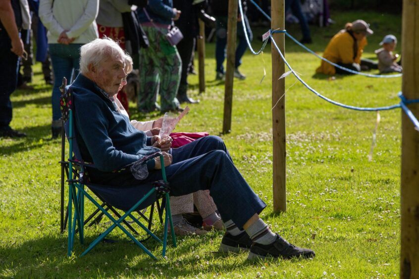 Elderly couple on foldable chairs beside Kenmore games field