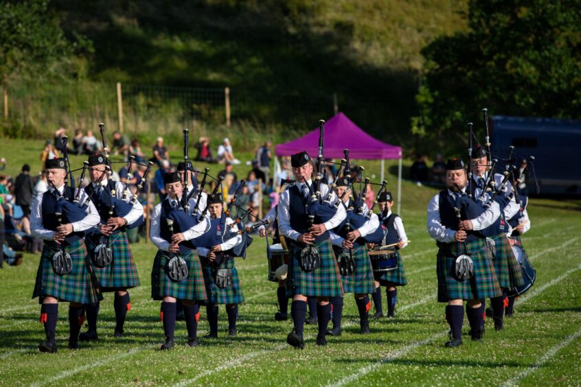 Vale of Atholl Pipe Band members on Kenmore games field watched by crowd