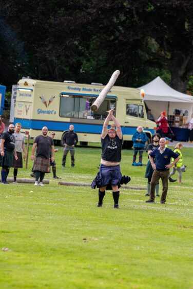 Heavy athlete in kilt tossing caber