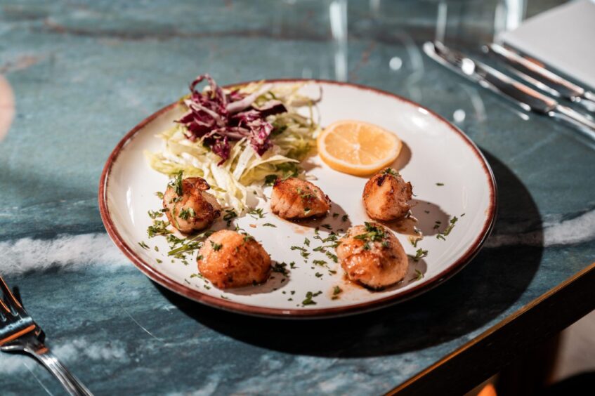 A plate of scallops served with a side salad.