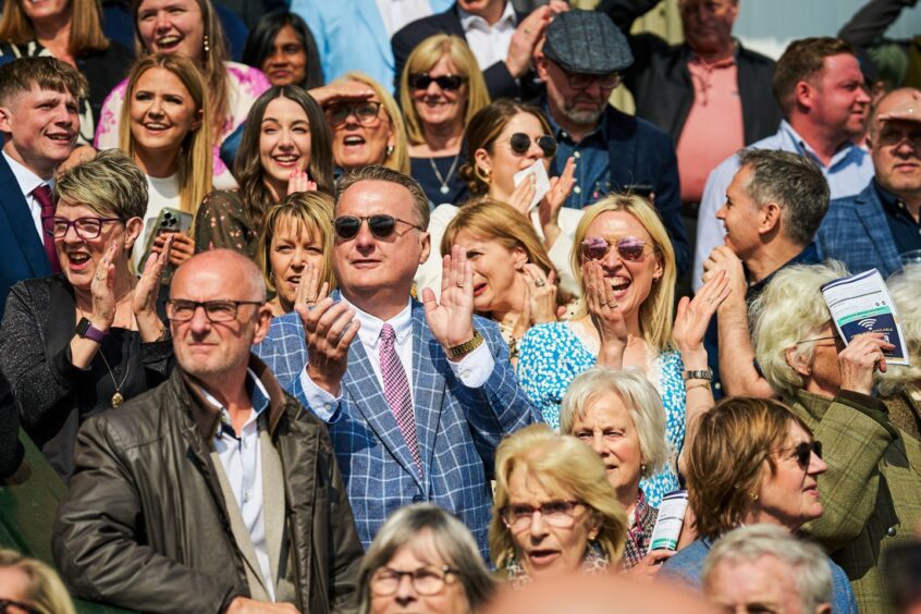 visitors who bought Perth Racecourse tickets cheer from the grandstand