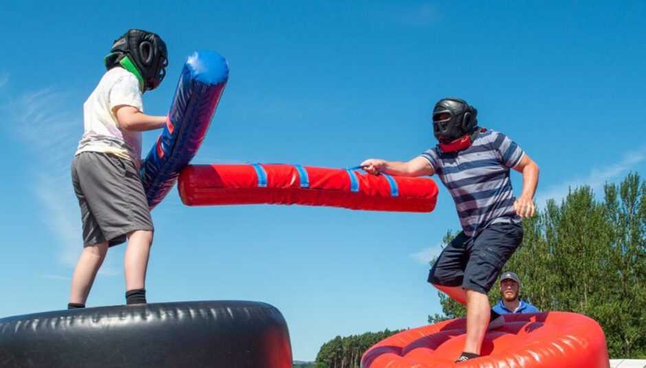 two children wearing protective helmets play an inflatable game