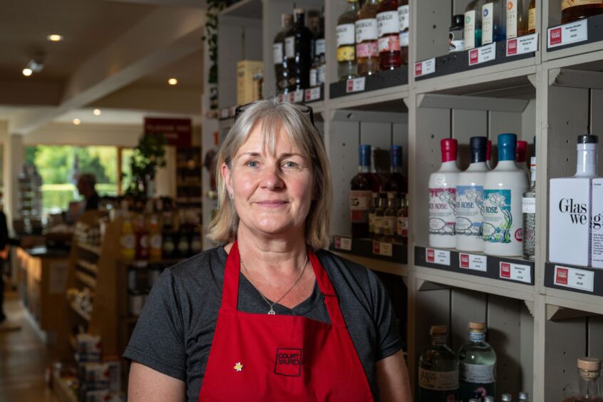 Lynne Mclaren posting beside display of alcohol