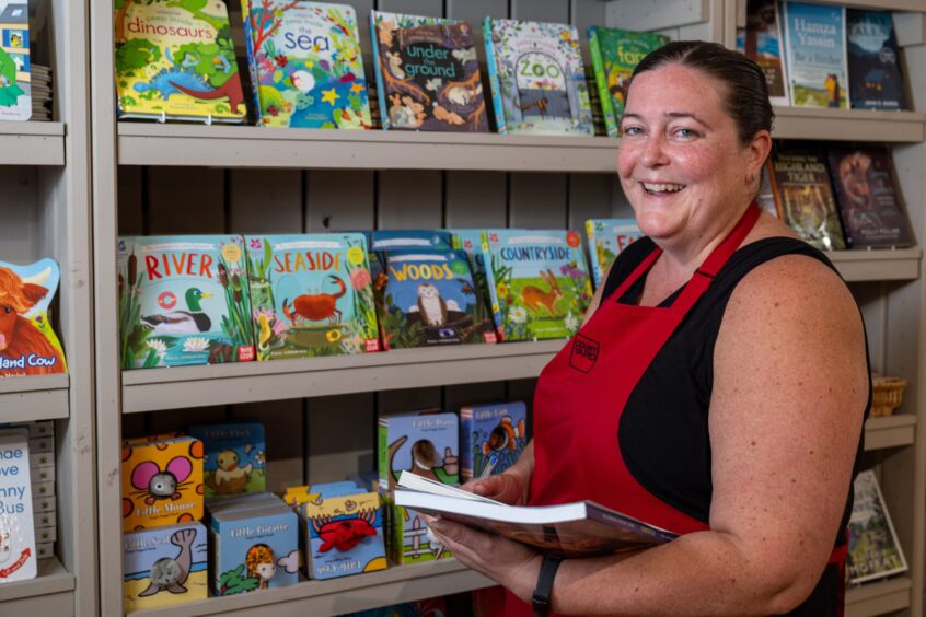 Jo Davies in red apron beside display of children's books