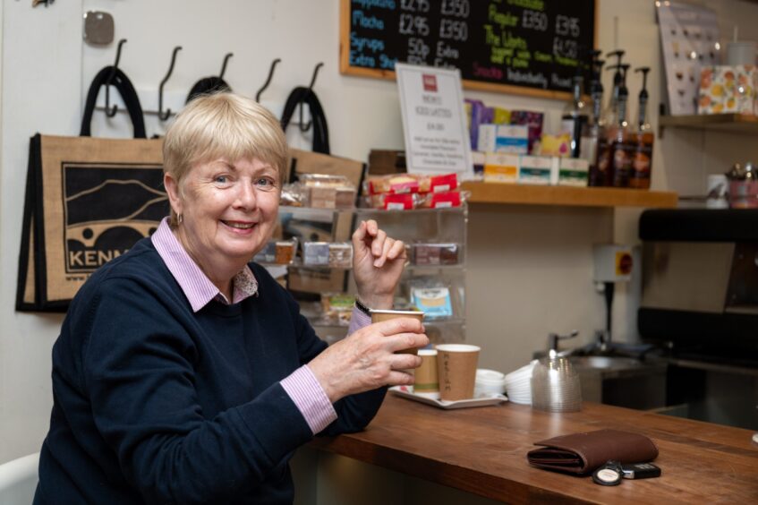 Joy McNally smiling as she holds her coffee cup