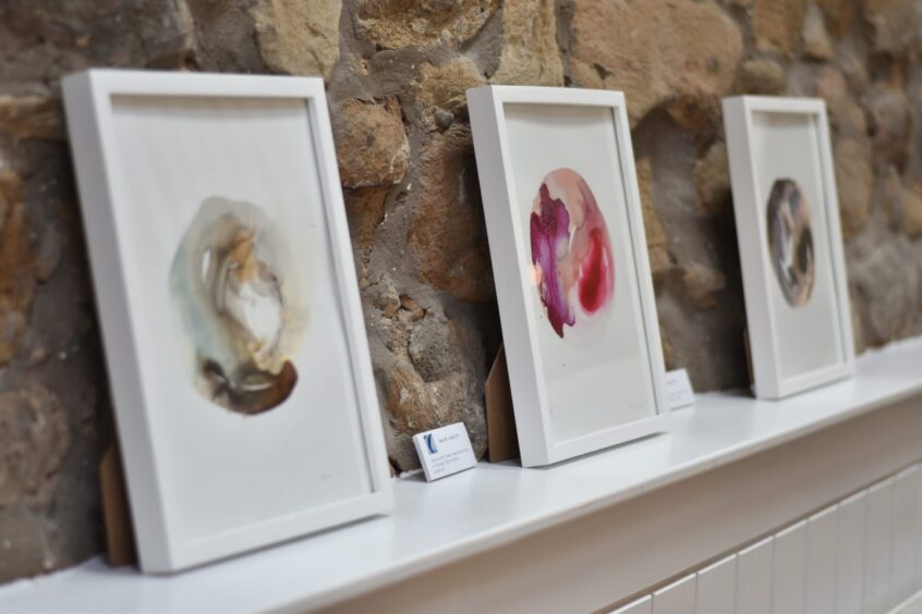 Artworks by Mira Caie leaning against the wall.