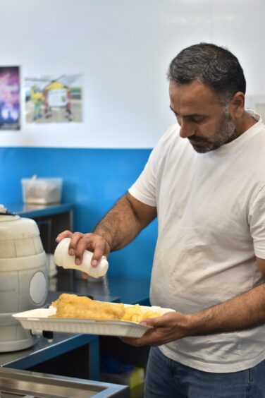 Kamran Ishaq adding salt to the fish and chips.