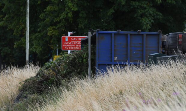 The bin lorry on its side with some of its contents on the road.