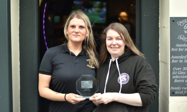 Marta Droszkowska Raynor and Laura McDermott standing with their trophy outside The Keys Bar.