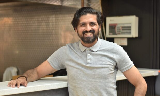 Fahad Usman, smiling in his restaurant.