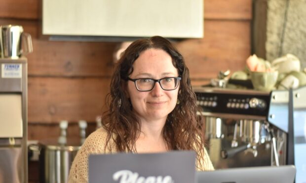 Jennifer De Vries smiling from behind a café counter.