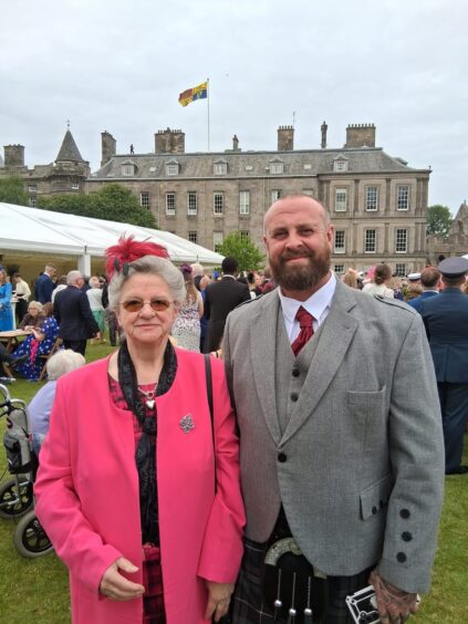 Irene Hamilton and John-Charles Burns-Hamilton with palace of Holyroodhouse and garden party behind