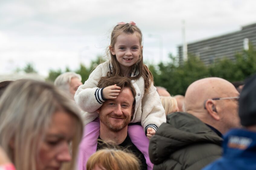 A little girl on her dad's shoulders gets a better view of the Discovery Festival stage.